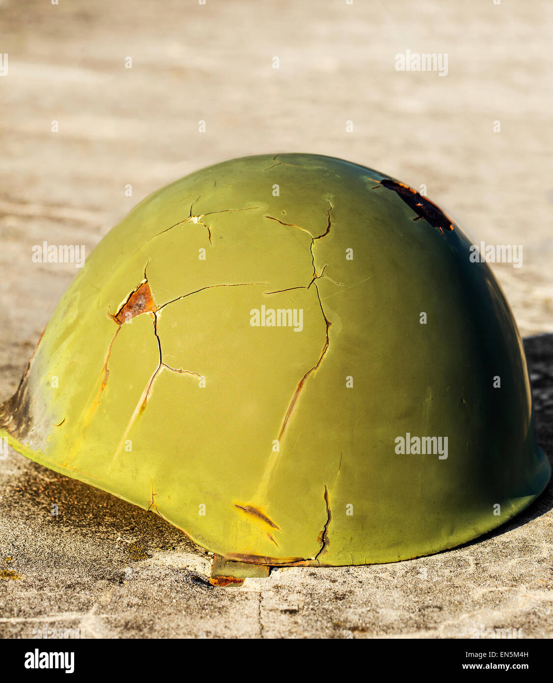 Green helmet used in war, placed on a concrete. Stock Photo