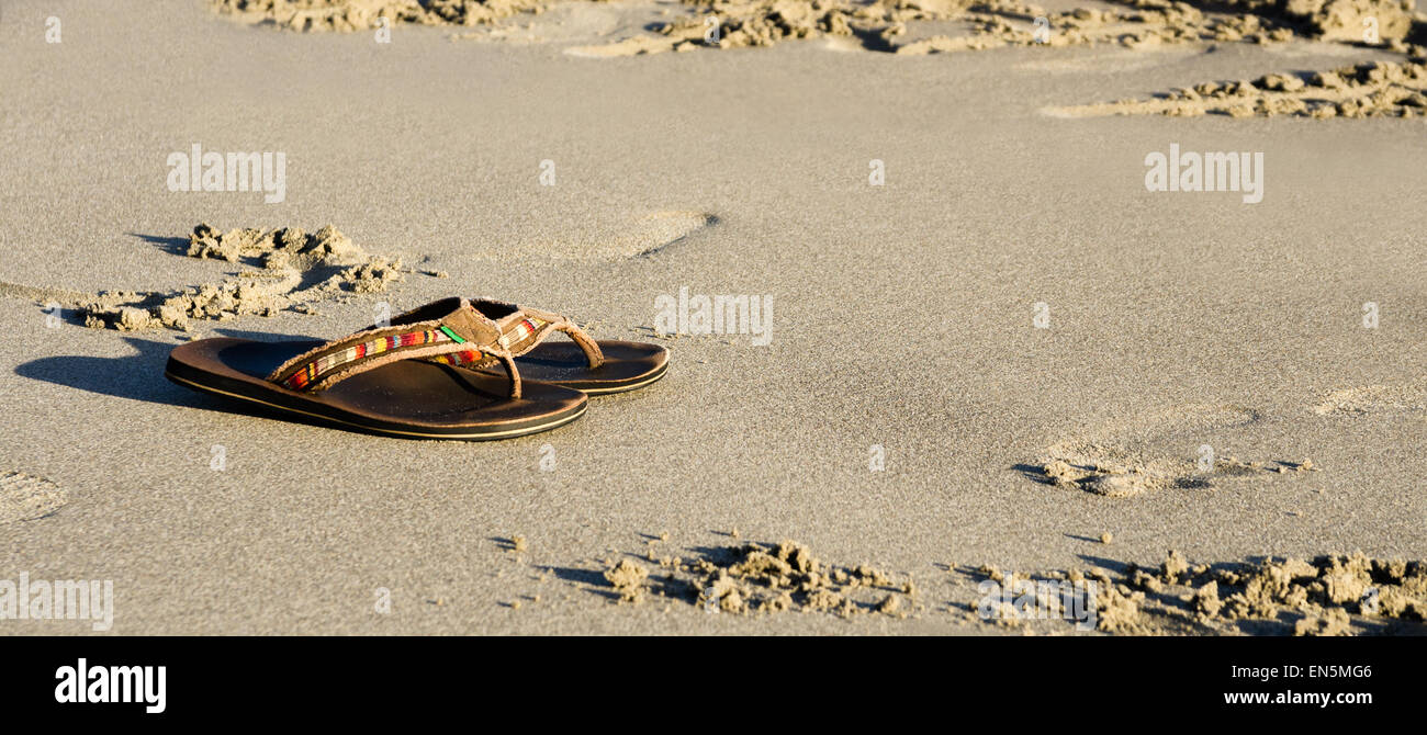 Slippers on a sand beach at sunset Stock Photo