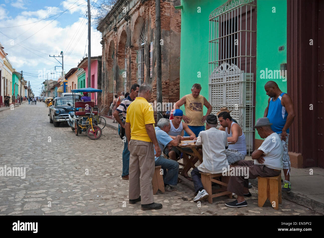 Horizontal view of a group of Cubans playing dominoes on the side of the road in Trinidad, Cuba. Stock Photo