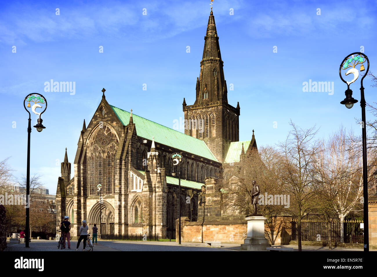 Tourists in Cathedral Square in front of the main entrance of St Mungo's Cathedral, Glasgow. Lamp-posts holding Glasgow coat of Stock Photo