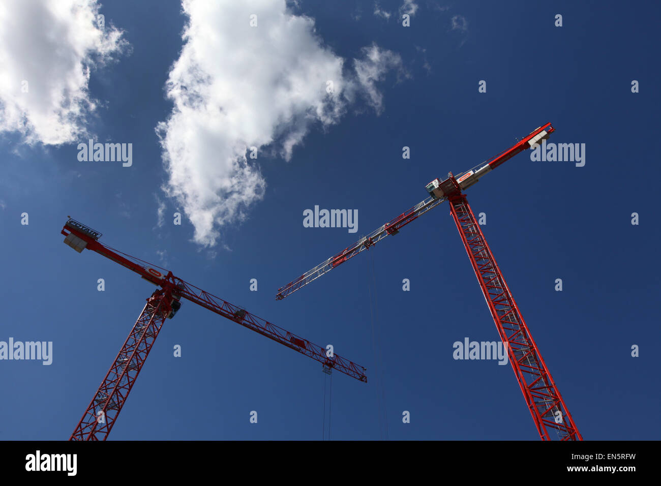 red cranes against a blue sky on a construction site Stock Photo