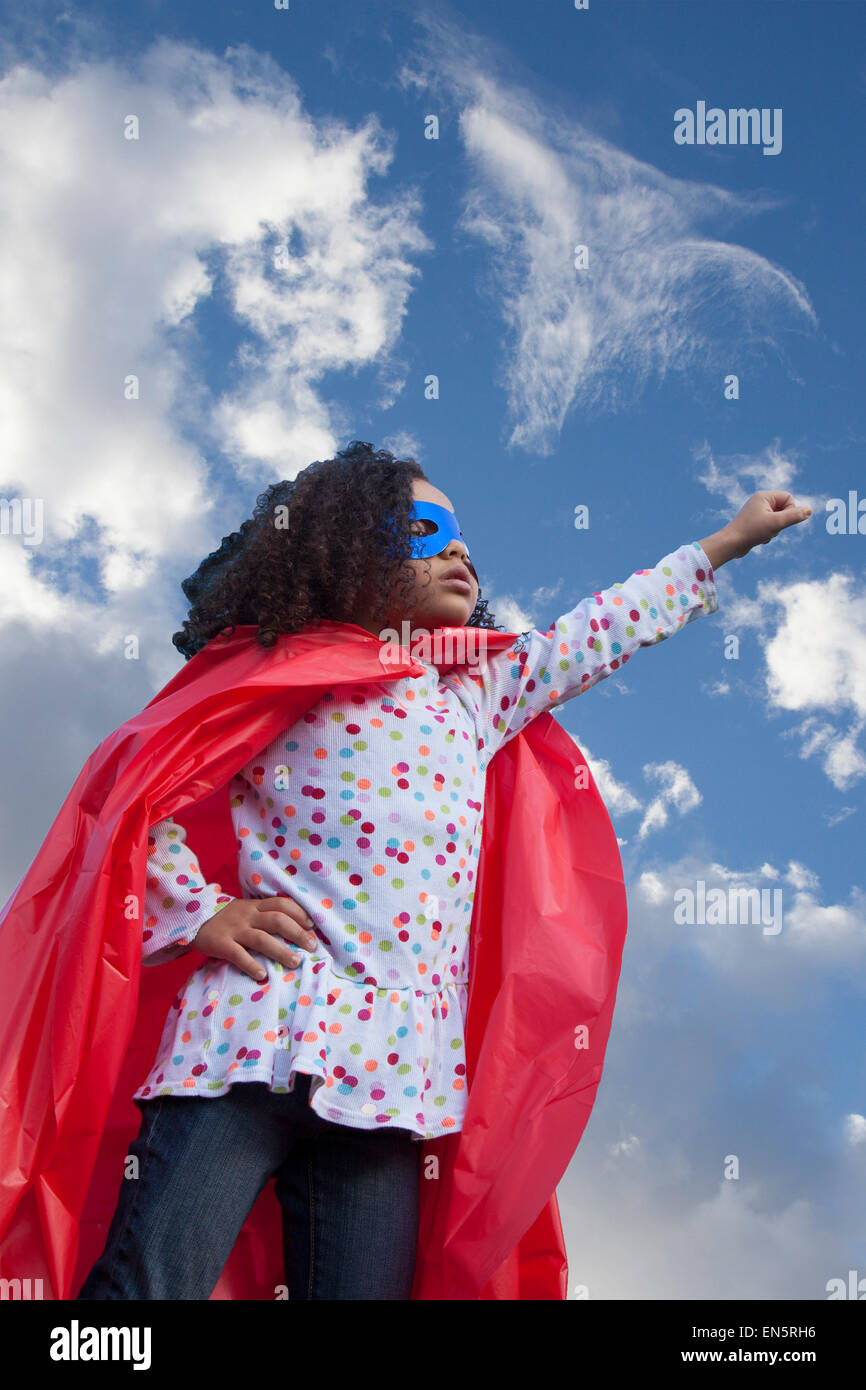 little girl superhero against blue sky Stock Photo