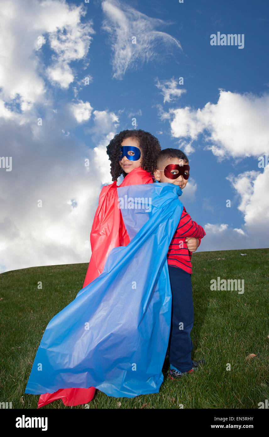 little boy and girl superheros against blue sky Stock Photo