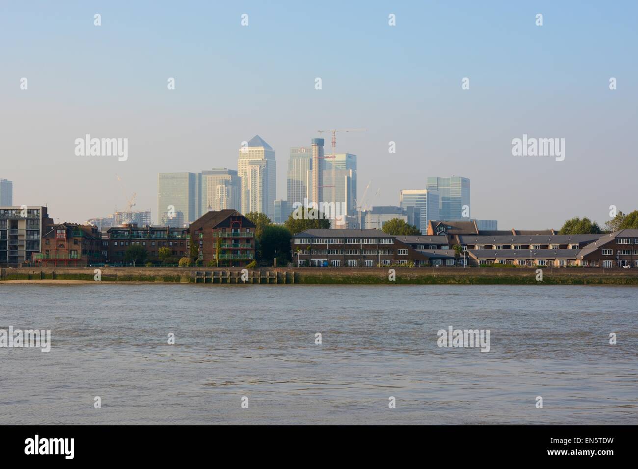 Modern skyscraper buildings at Docklands in London, England. With River Thames and houses in foreground. Misty and hazy Stock Photo