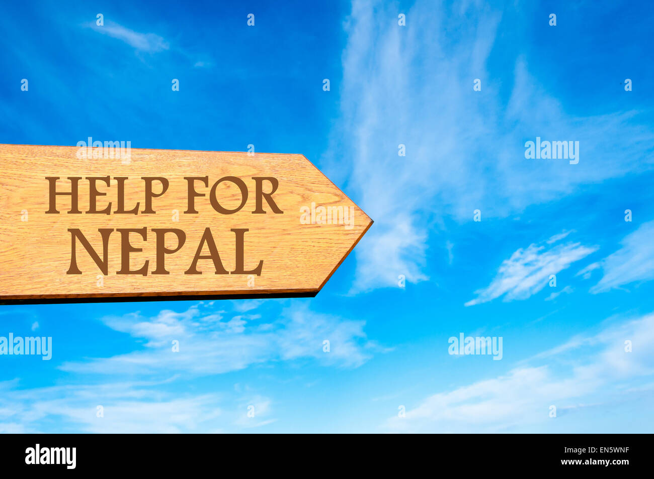 Wooden arrow sign with message HELP FOR NEPAL against clear blue sky ...
