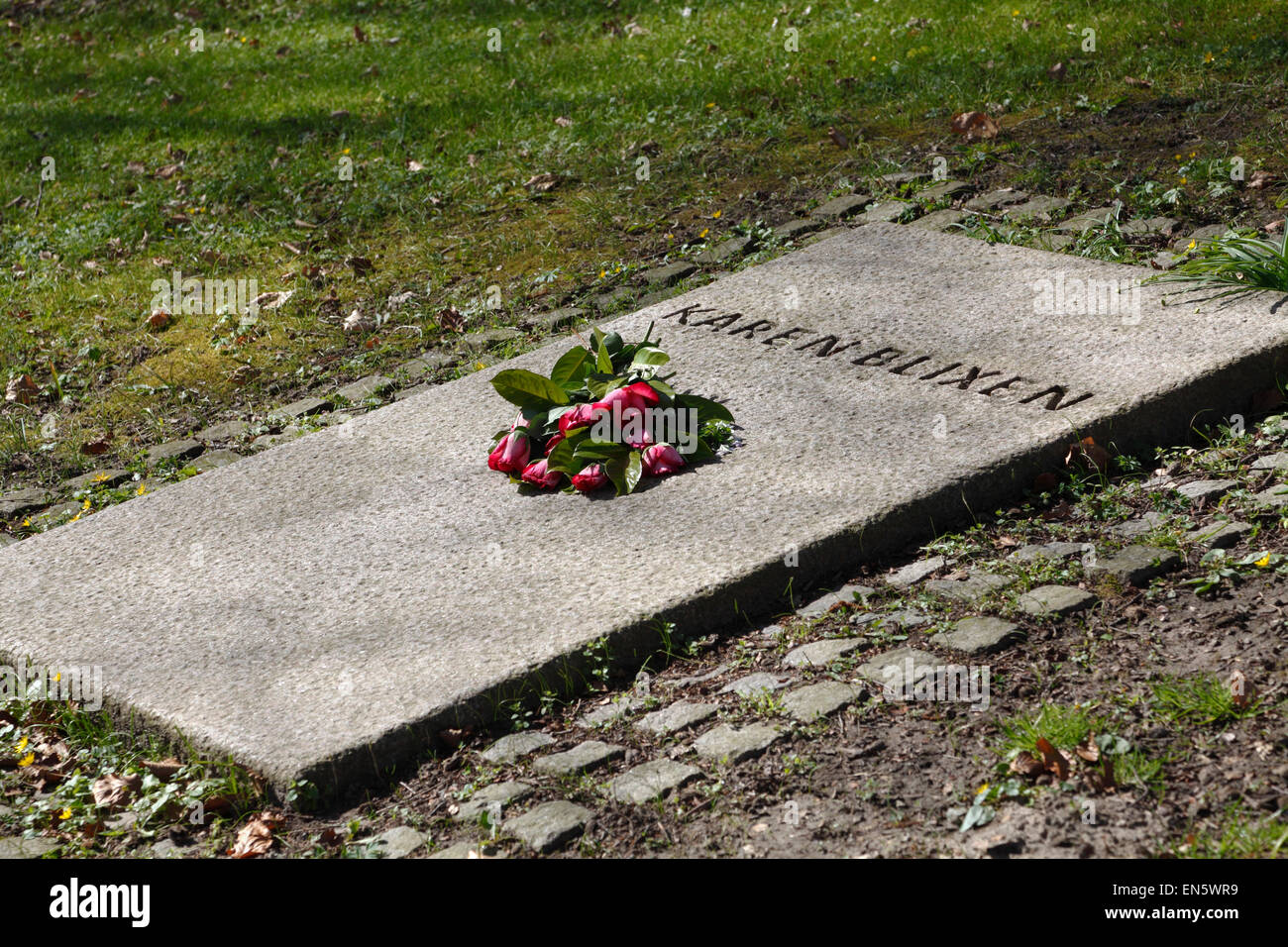 Karen Blixen's grave with fresh red roses on a sunny spring day at Rungstedlund the day after her 130th birthday. Stock Photo