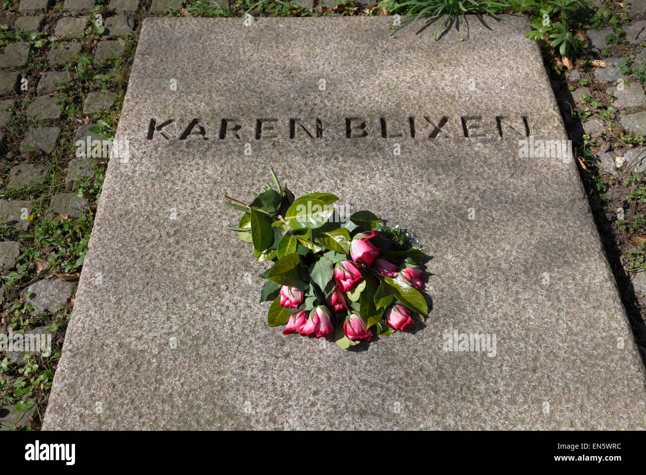 Karen Blixen's grave with fresh red roses on a sunny spring day at Rungstedlund the day after her 130th birthday. Stock Photo