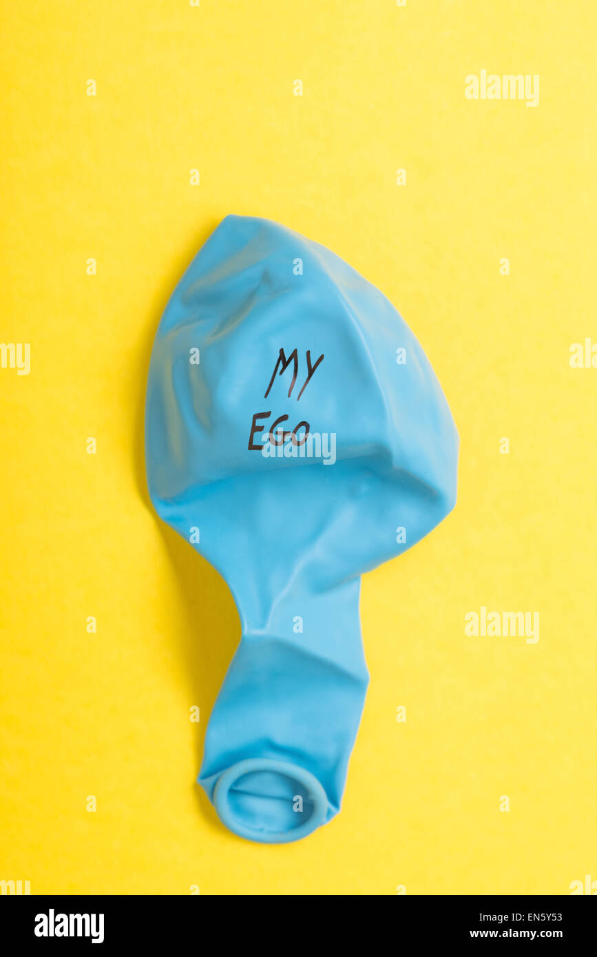 Deflated blue balloon on yellow background with the words my ego on it Stock Photo