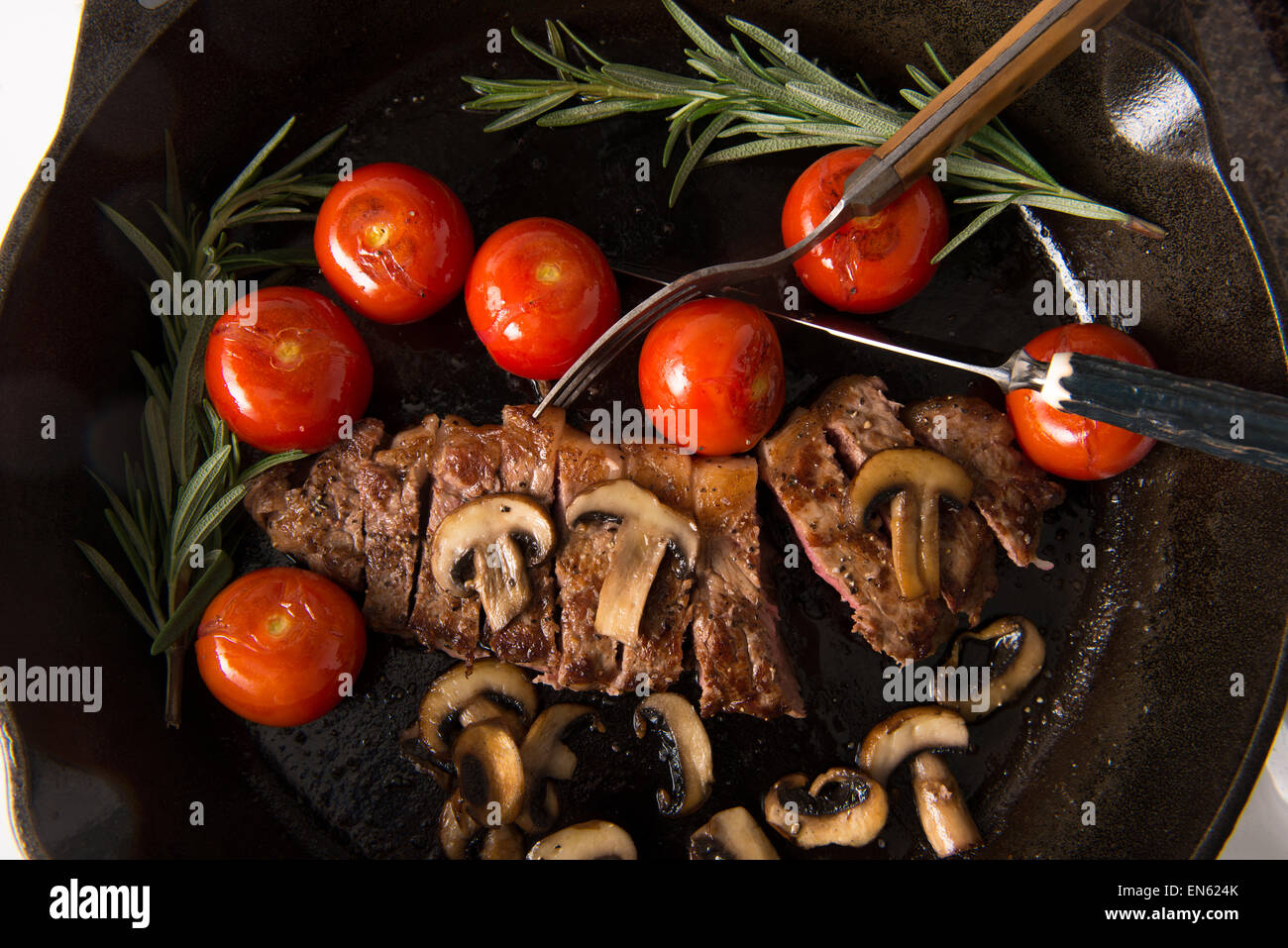 Grilling Strip Loin Steak in Cast Iron Frying Pan Steak is cooked and sliced shown with