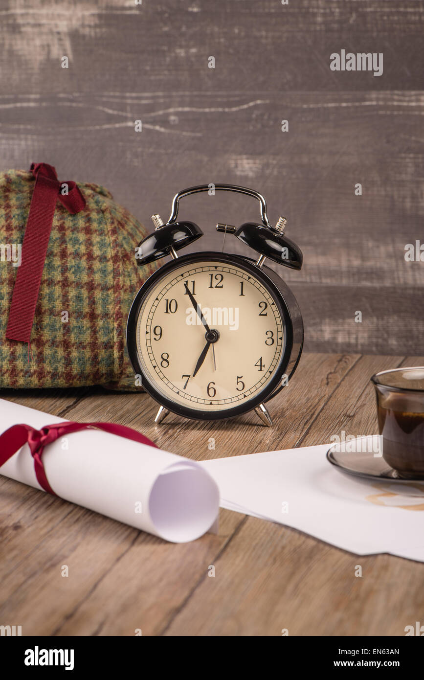 Old clock, hat coffee and paper sheets on old Wooden table. Stock Photo