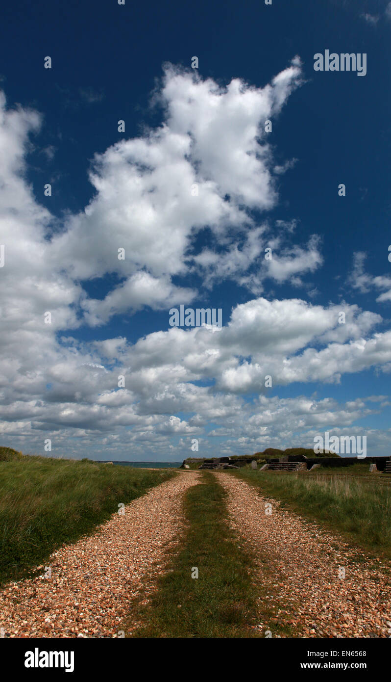 A gravel path leading into the distance with clouds against a blue sky Stock Photo