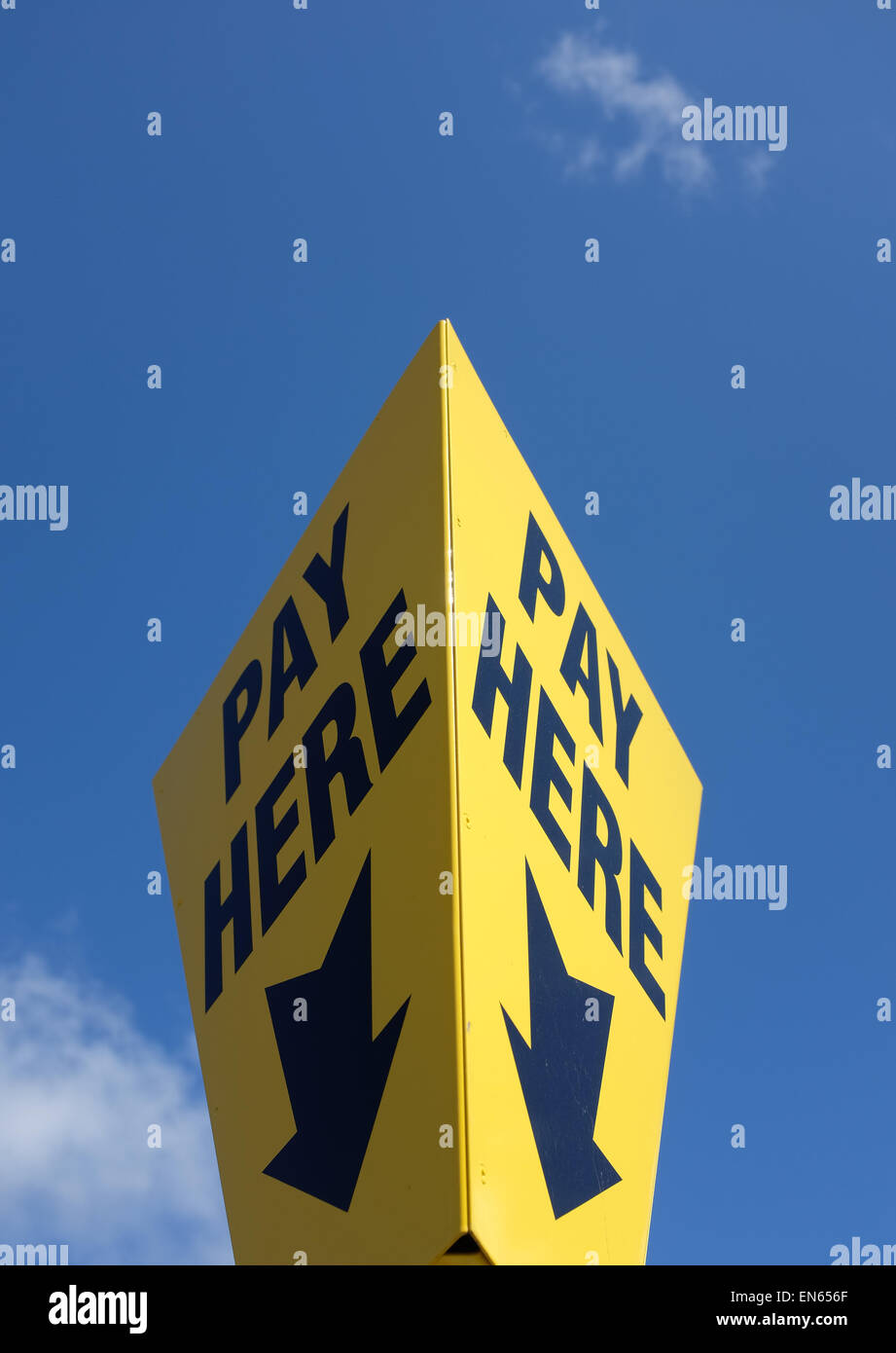 Yellow pay here sign against a blue sky background with copy space Stock Photo