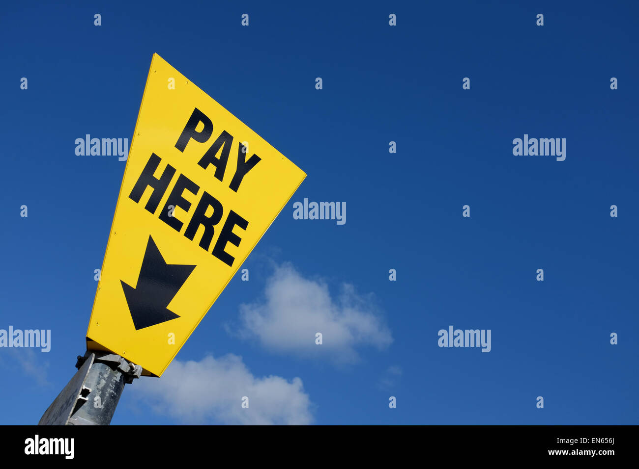 Yellow pay here sign against a blue sky background with copy space Stock Photo