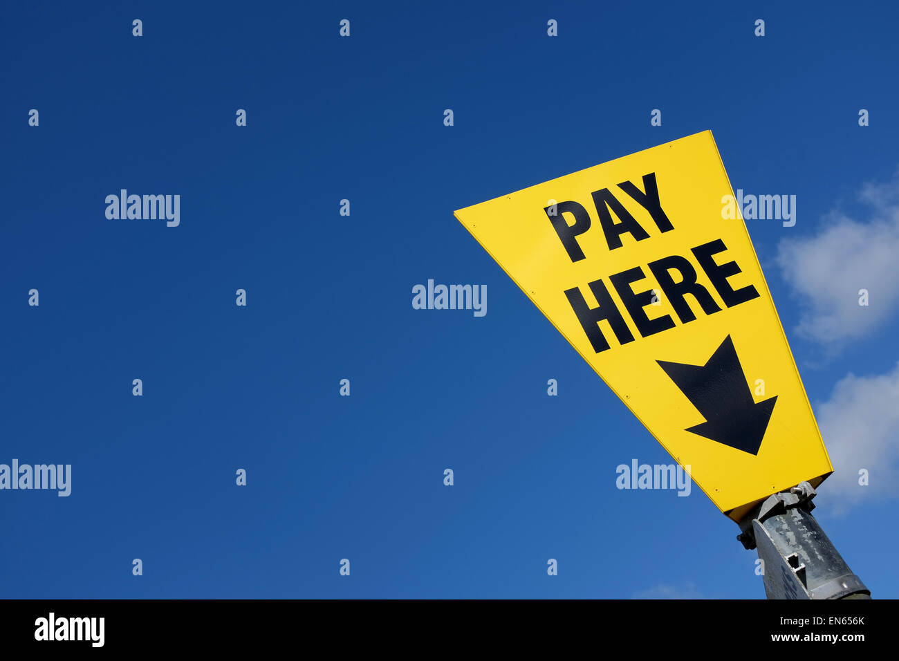 Yellow pay here sign against a blue sky background with copy space Stock Photo