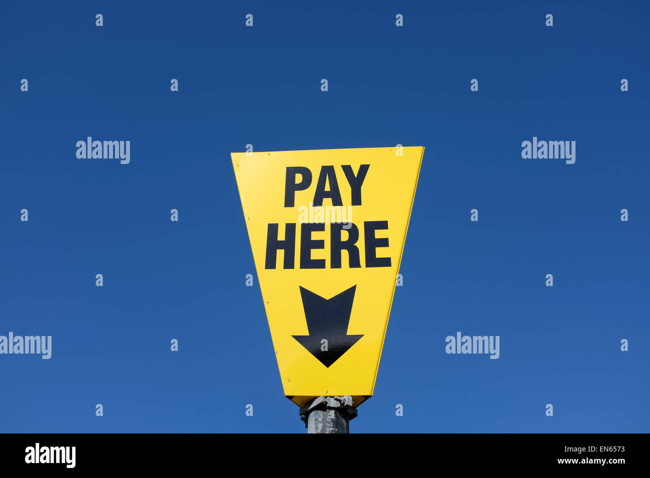 Yellow pay here sign against a blue sky background with copy space Stock Photo