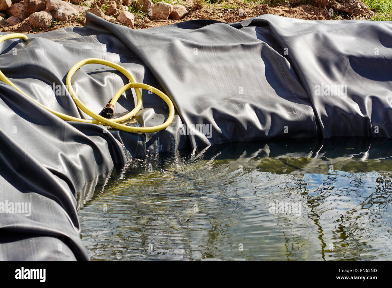 New pond with rubber liner is being filled with water for the first time. Stock Photo