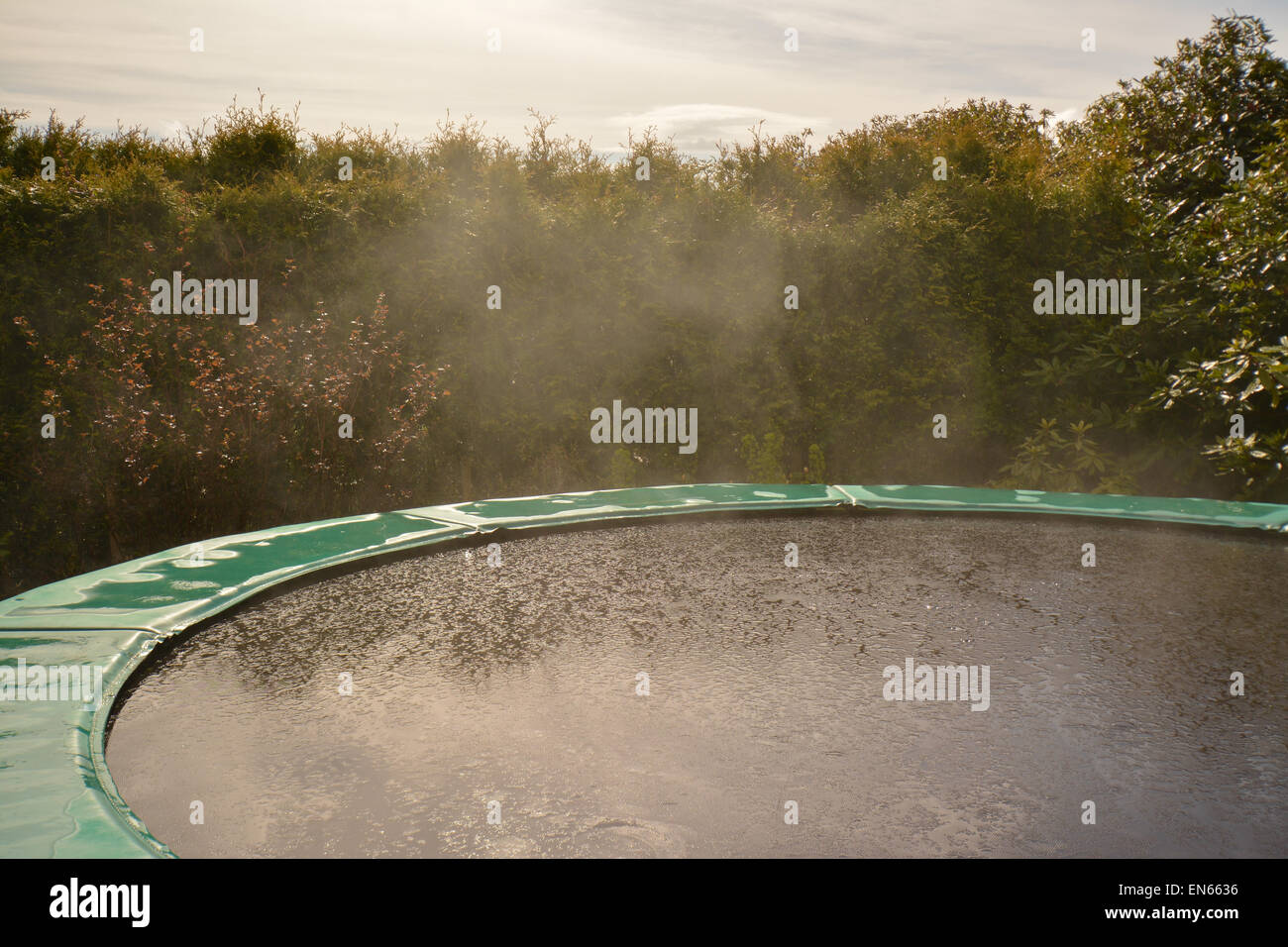 example of evaporation for children - rain evaporating from garden trampoline after sudden shower of rain Stock Photo