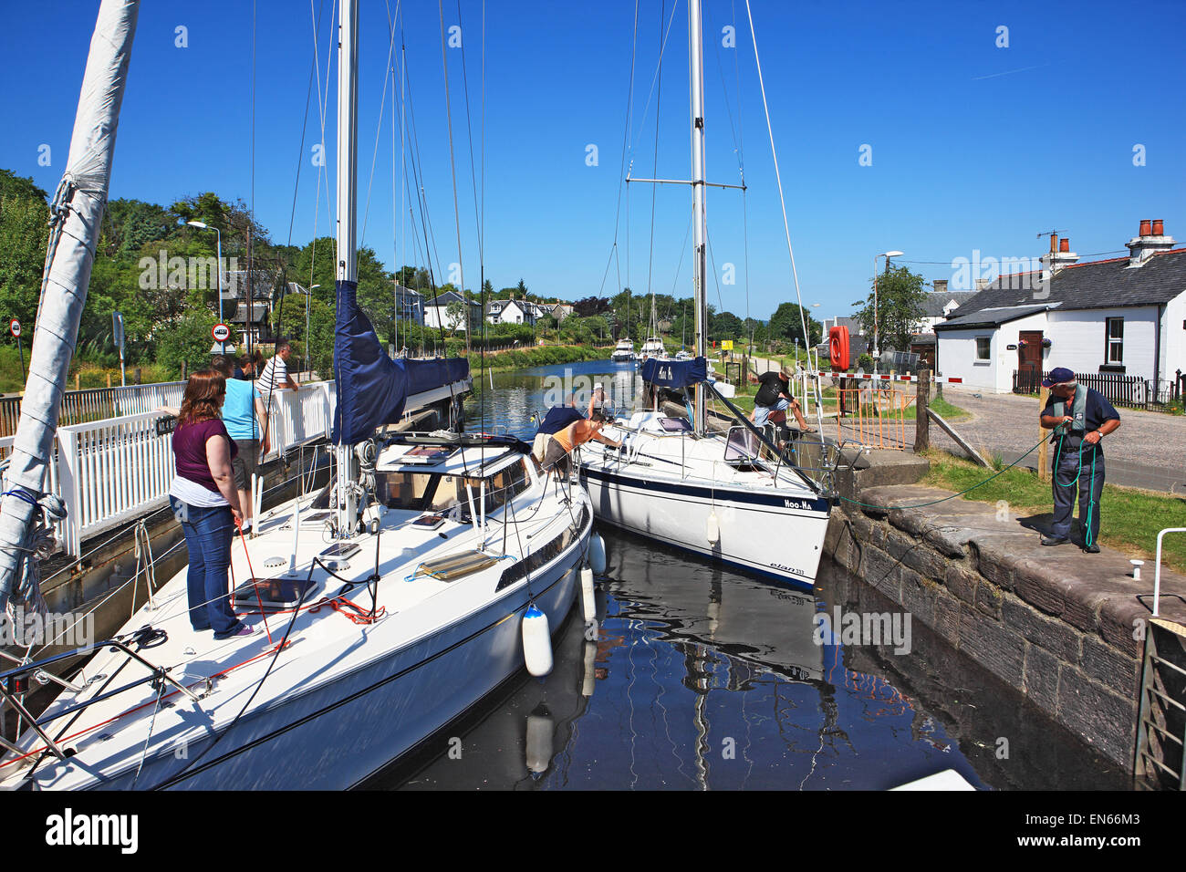 Yacht being guided by the lock keeper into lock 4 at the Ardrishaig swing bridge on the Crinan Canal in Argyllshire Scotland Stock Photo