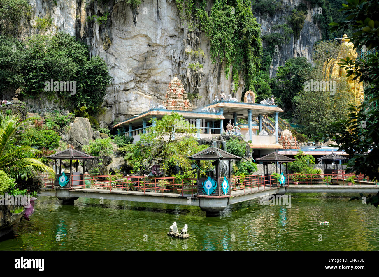 Exterior of a hindu temple in nature, between a pond and a cliff face, with cave behind. Hinduism, religion, religious building, temples, Hindu shrine Stock Photo