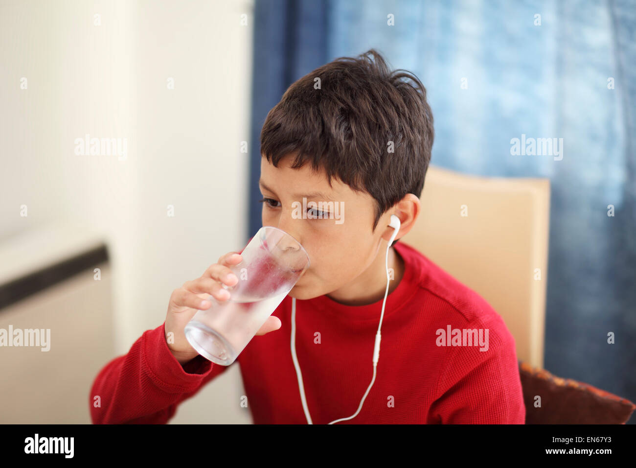 Young boy drinking from a glass of water while watching the computer - with shallow depth of field Stock Photo