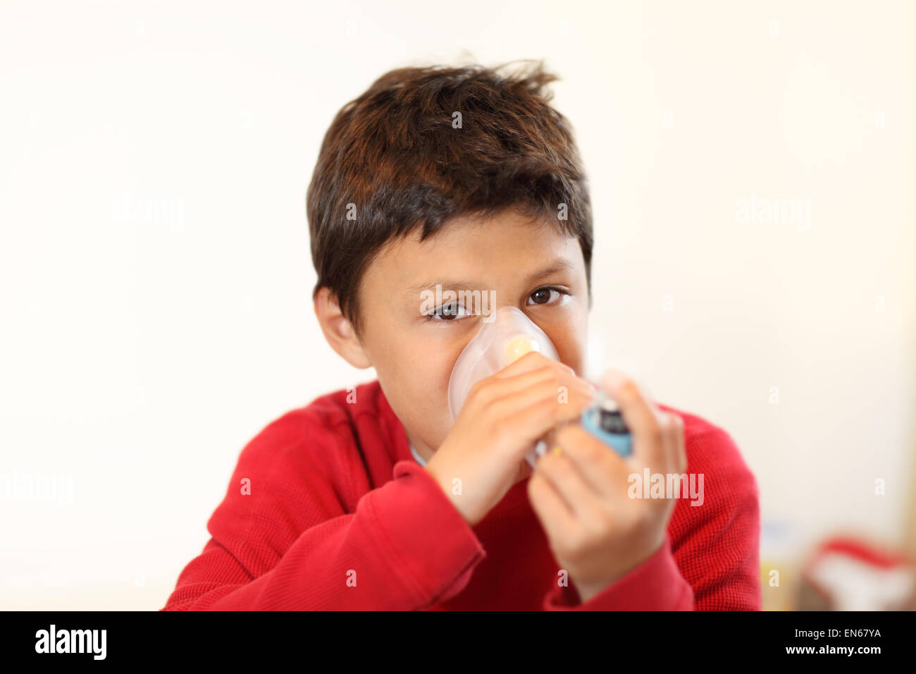 Young boy using inhaler on white background - with shallow depth of field Stock Photo