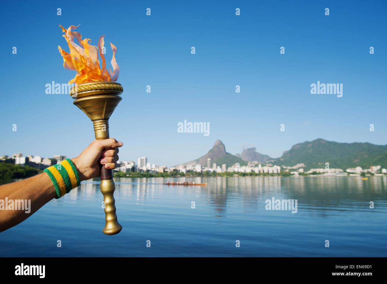 Hand of an athlete wearing sweatband holding sport torch against Rio de Janeiro Brazil skyline with Two Brothers Mountain Stock Photo