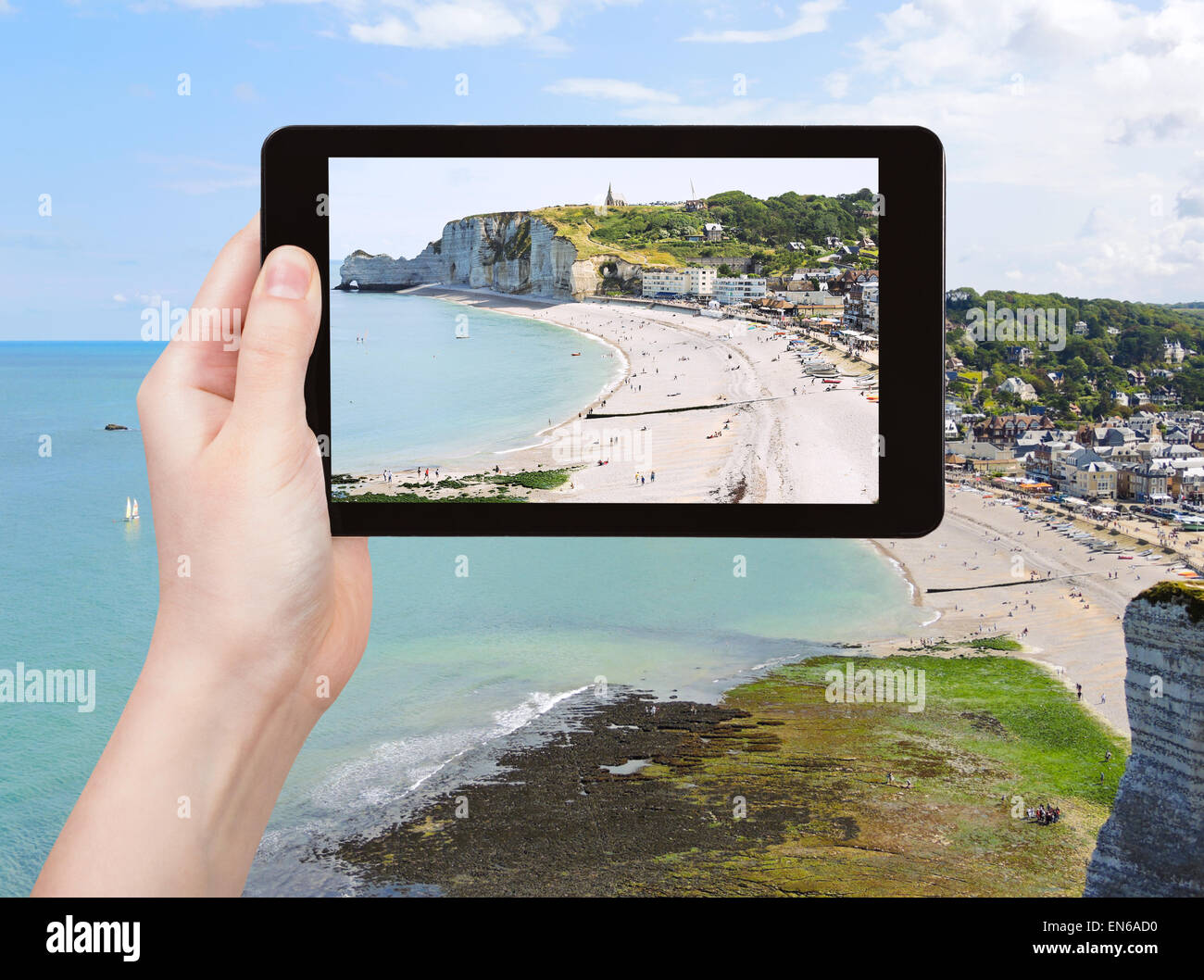 travel concept - tourist takes picture of Etretat resort village on english channel beach of cote d'albatre, France on tablet pc Stock Photo
