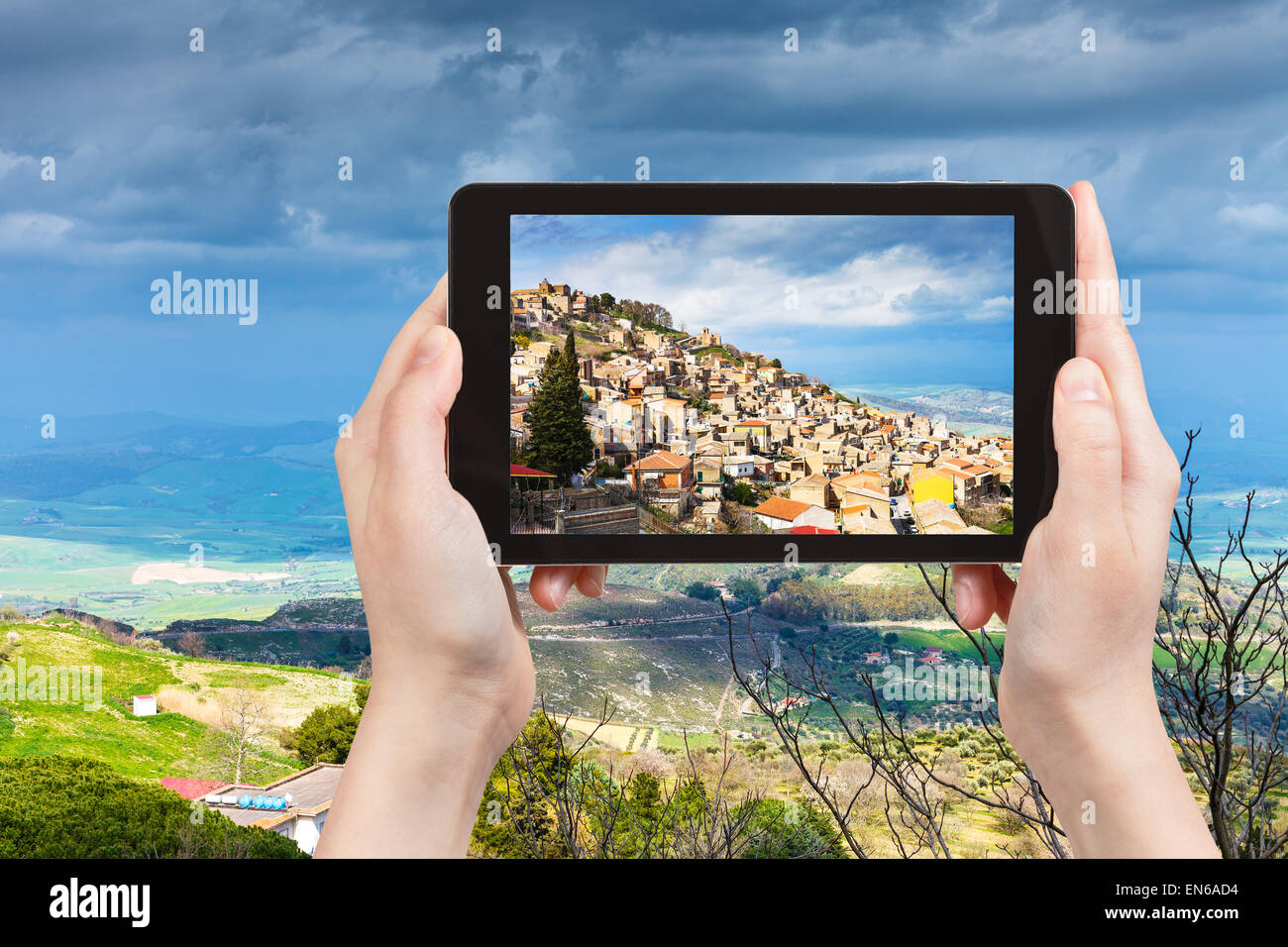 travel concept - tourist takes picture of Aidone town in Sicily in spring, Italy on tablet pc Stock Photo