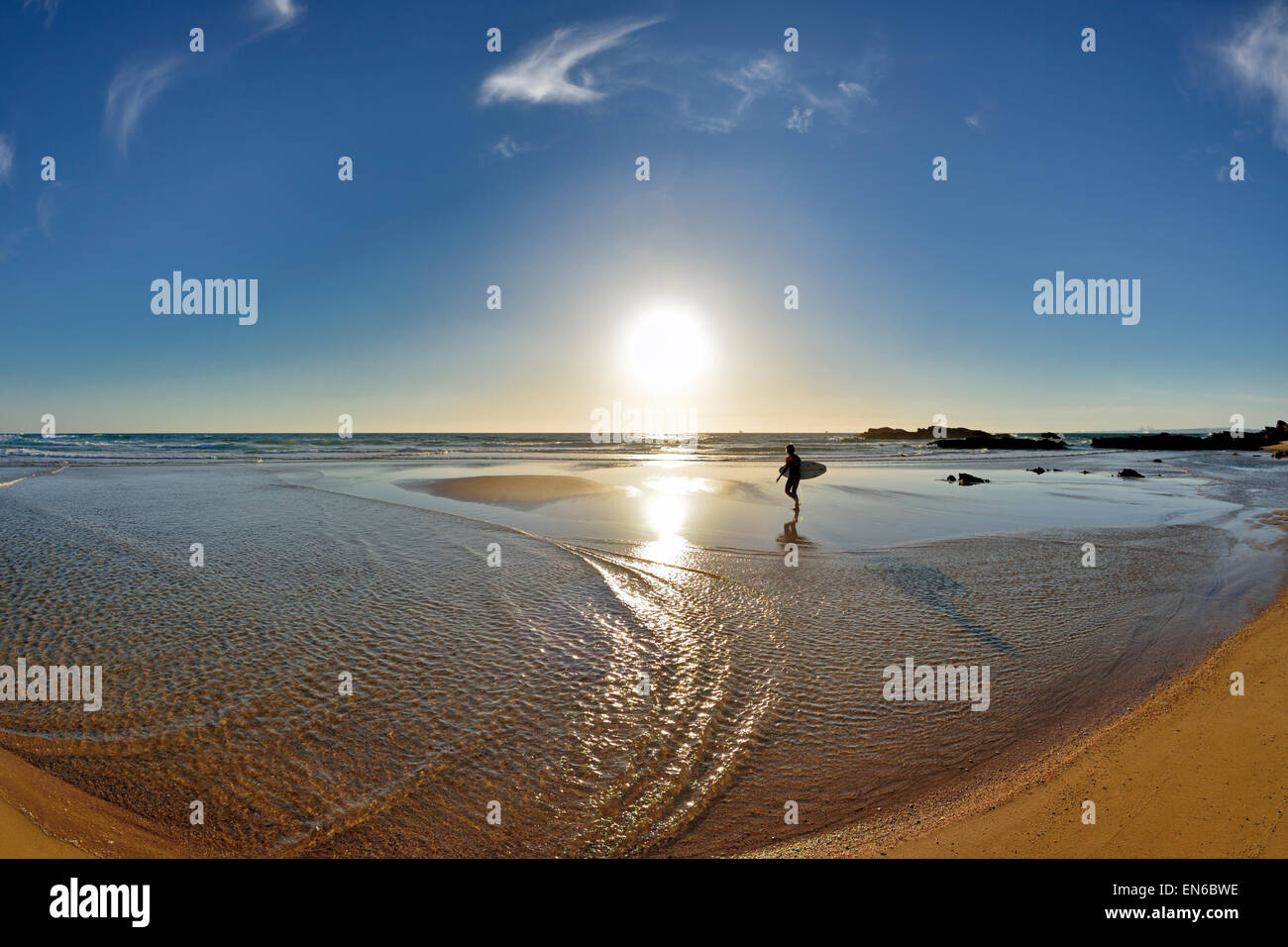 Portugal, Alentejo: Lonely surfer walking at scenic beach in Porto Covo Stock Photo