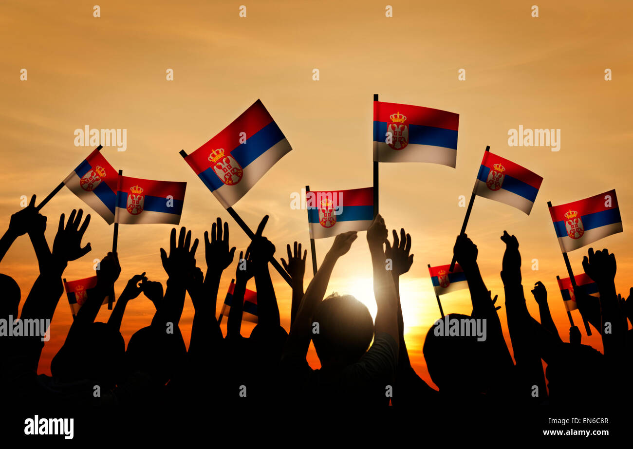 Group of People Waving Flag of Serbia in Back Lit Stock Photo