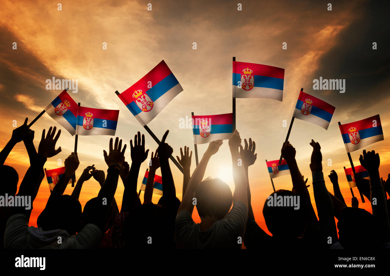 Group of People Waving Flag of Serbia in Back Lit Stock Photo