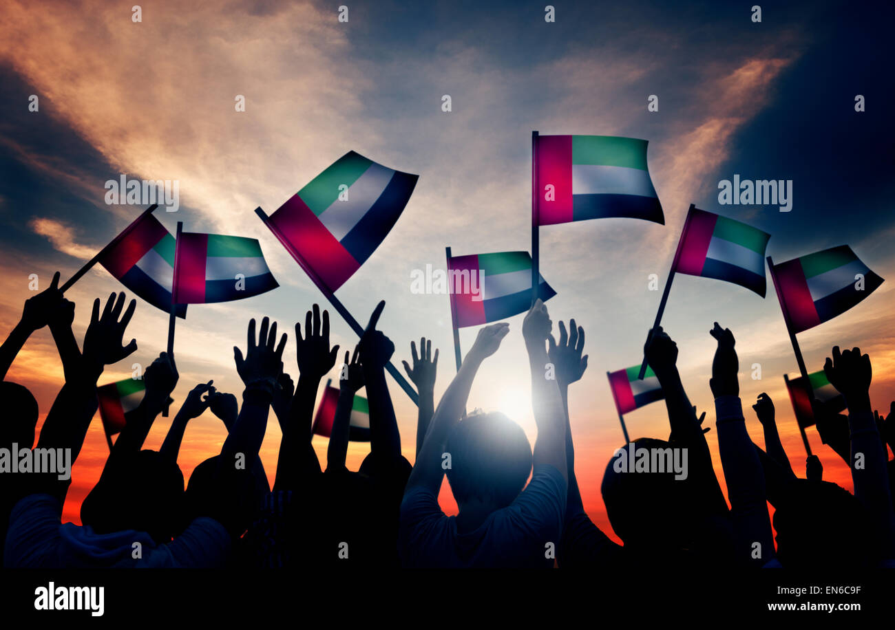 Group of People Waving Flag of UAE in Back Lit Stock Photo