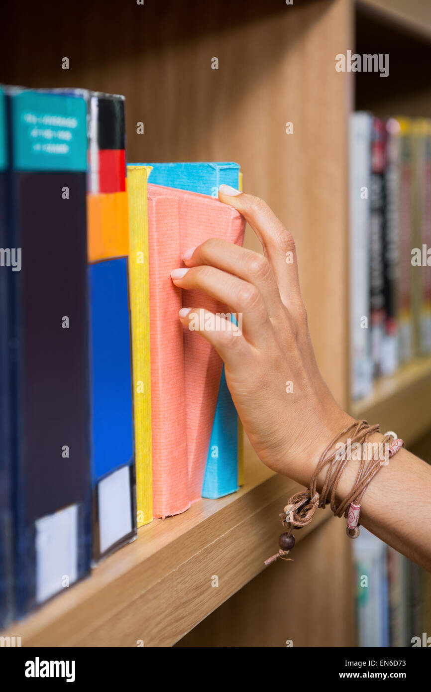 Student picking a book from shelf in library Stock Photo