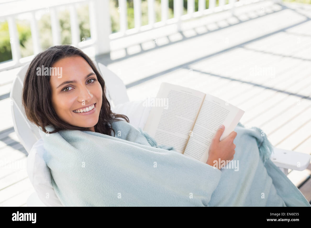 Pretty brunette sitting on a chair and reading a book Stock Photo - Alamy