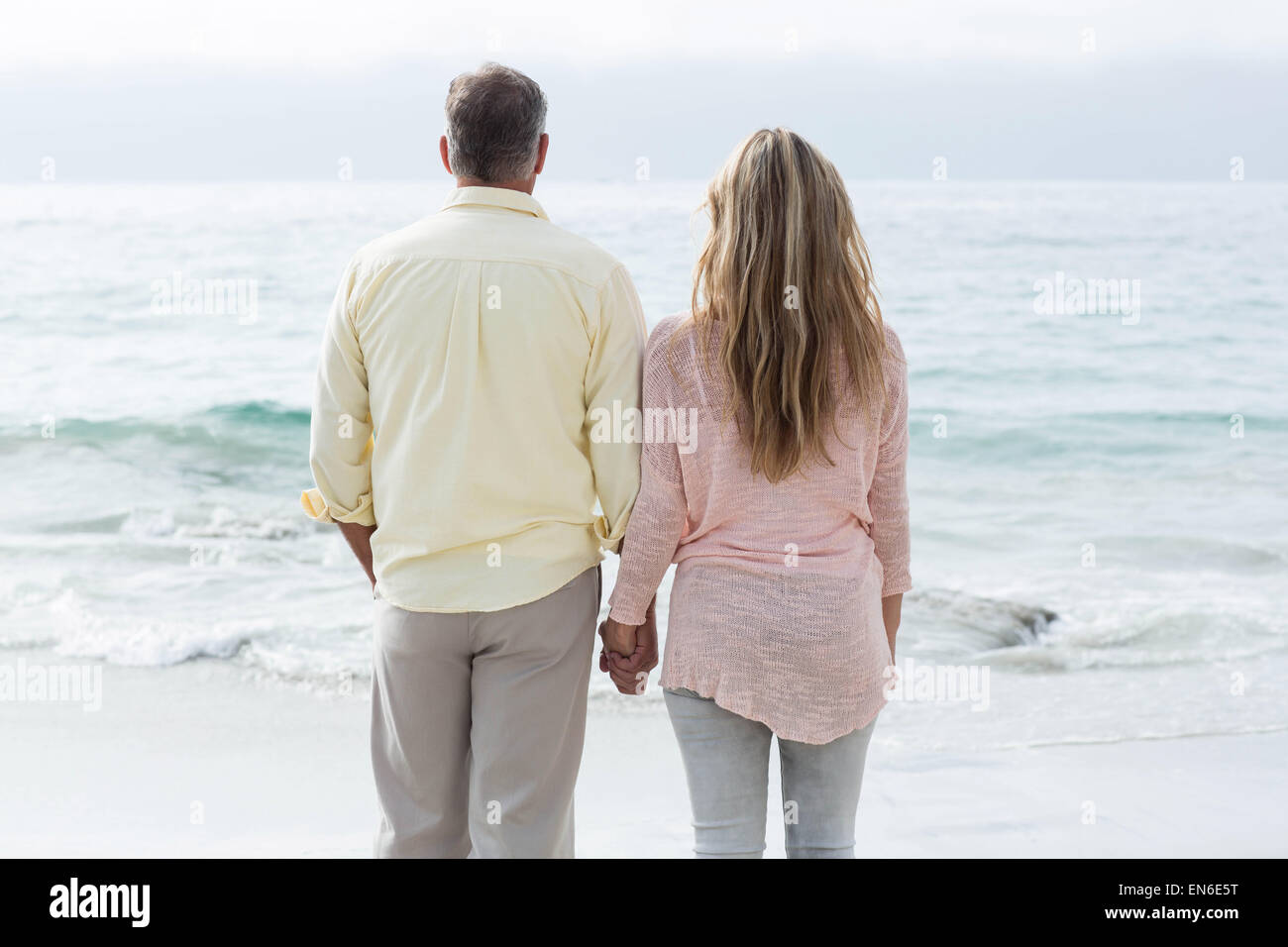 Happy couple standing by the sea and holding hands Stock Photo - Alamy