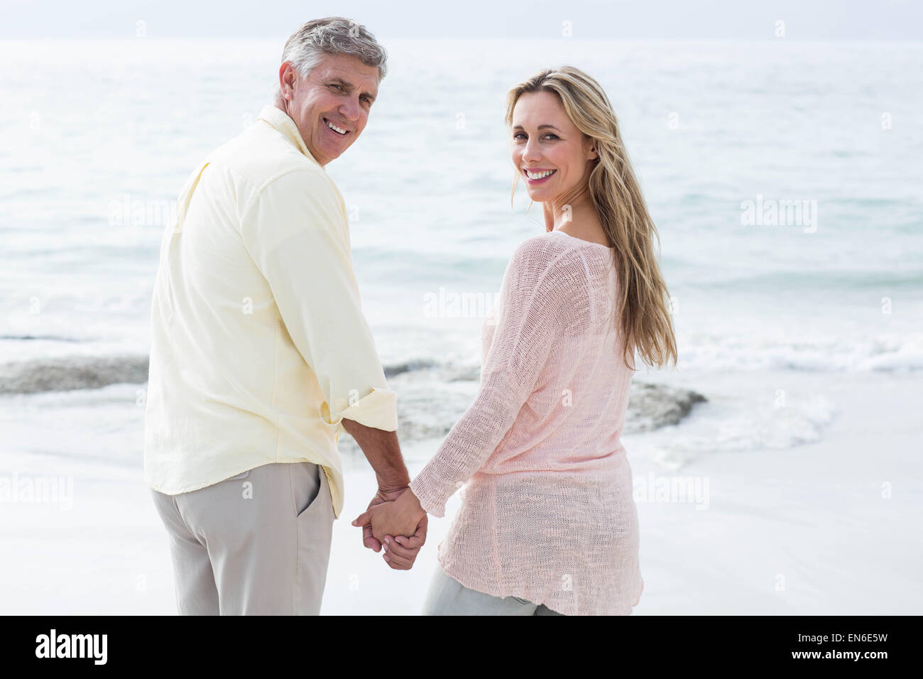 Happy couple standing by the sea and holding hands Stock Photo - Alamy
