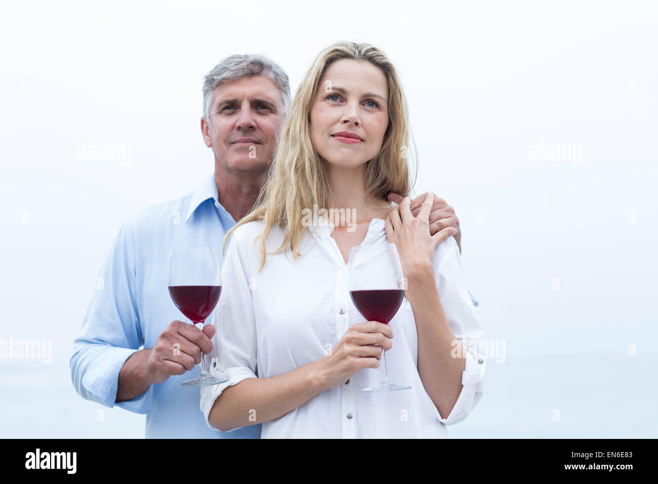 Happy couple holding a glass of red wine Stock Photo - Alamy