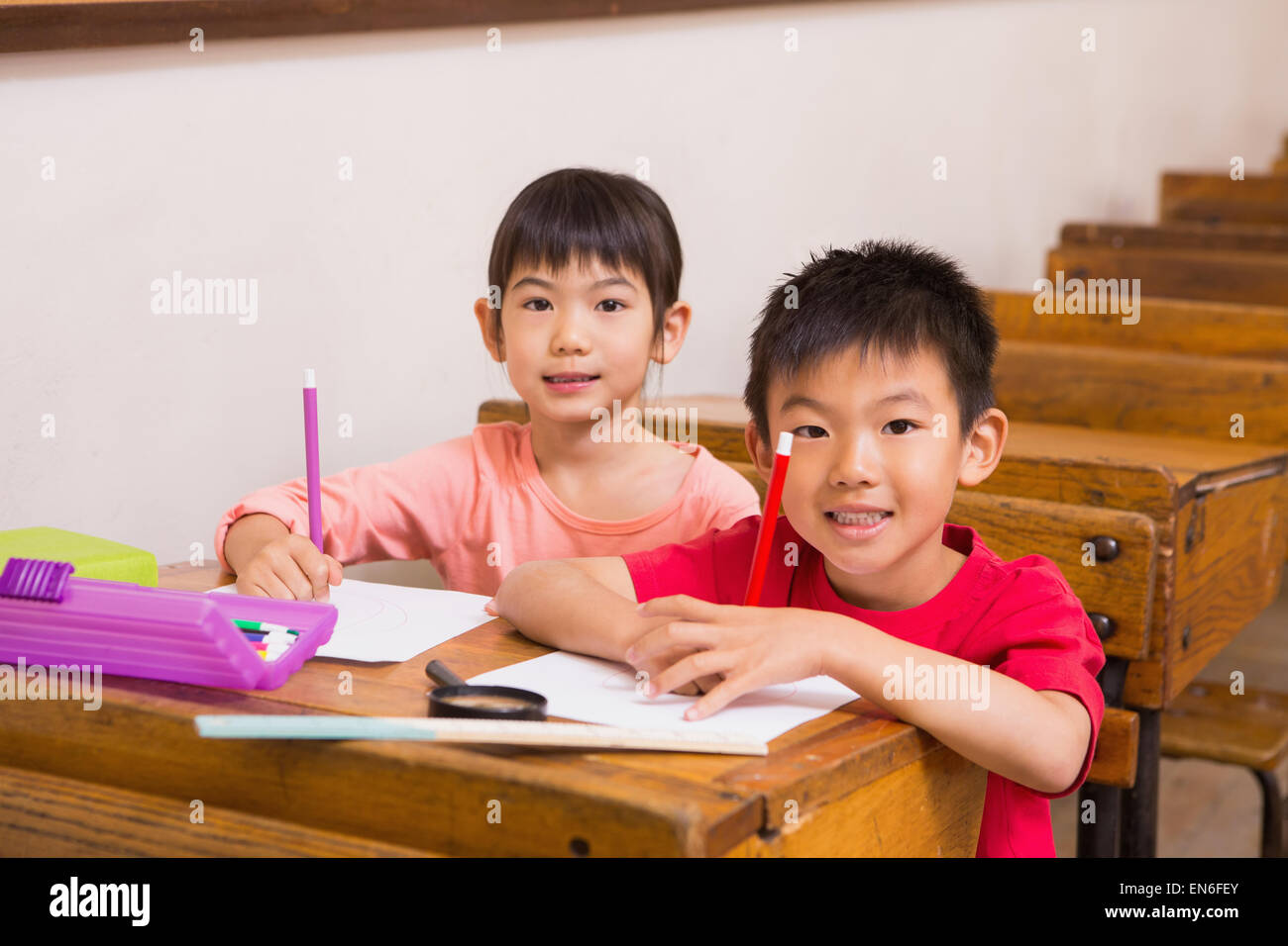 Cute pupils smiling at camera in classroom Stock Photo - Alamy