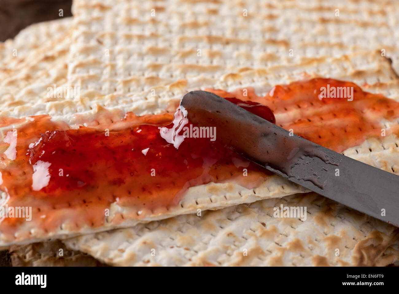 Matzah, served here with strawberry preserves,  the unleavened bread used in the Jewish holiday passover, set on wood bowl in ru Stock Photo