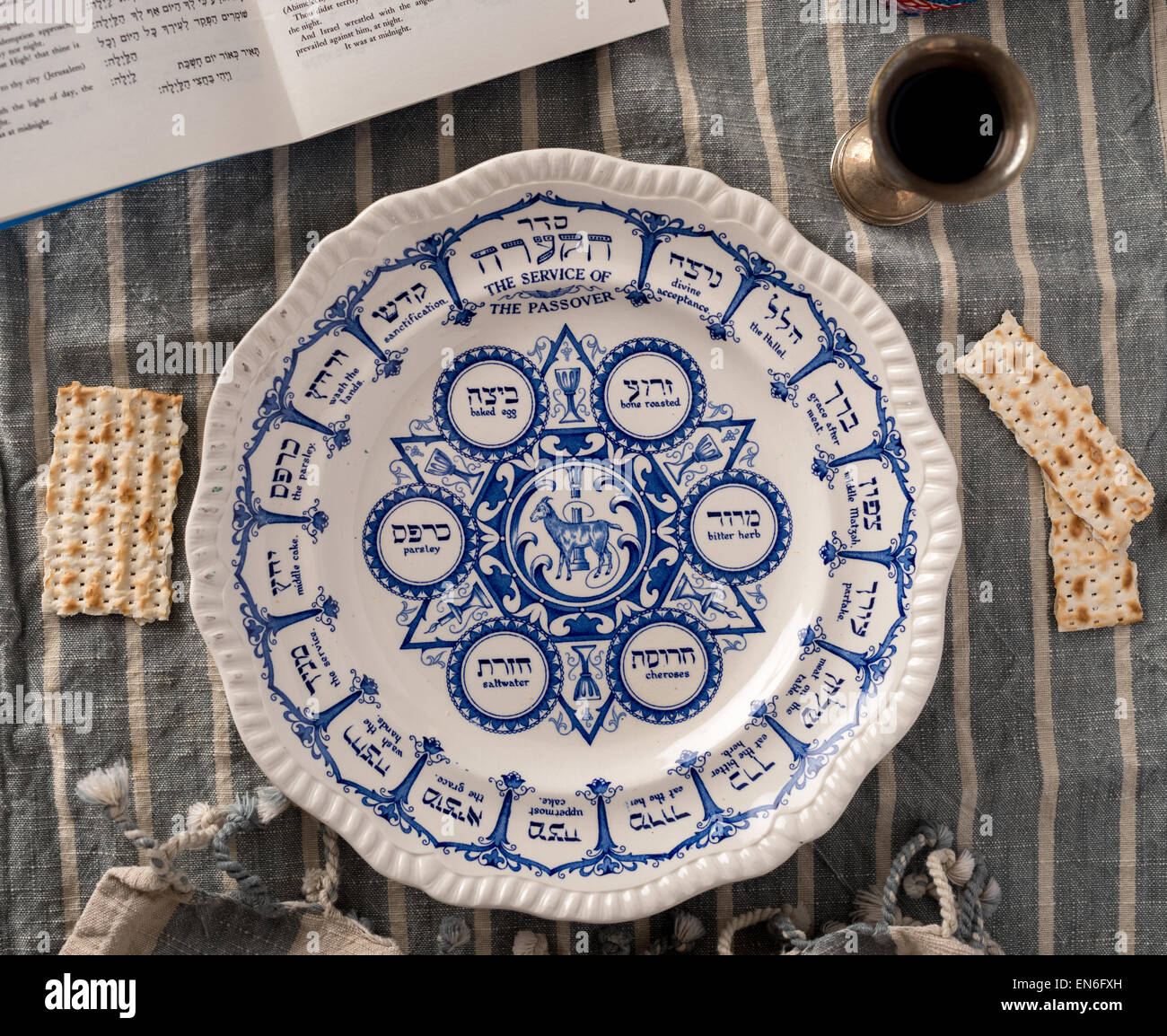 Vintage traditional passover plate, used during the Jewish holiday is show with the habbadah, kiddush cup and colourful yarmulke Stock Photo