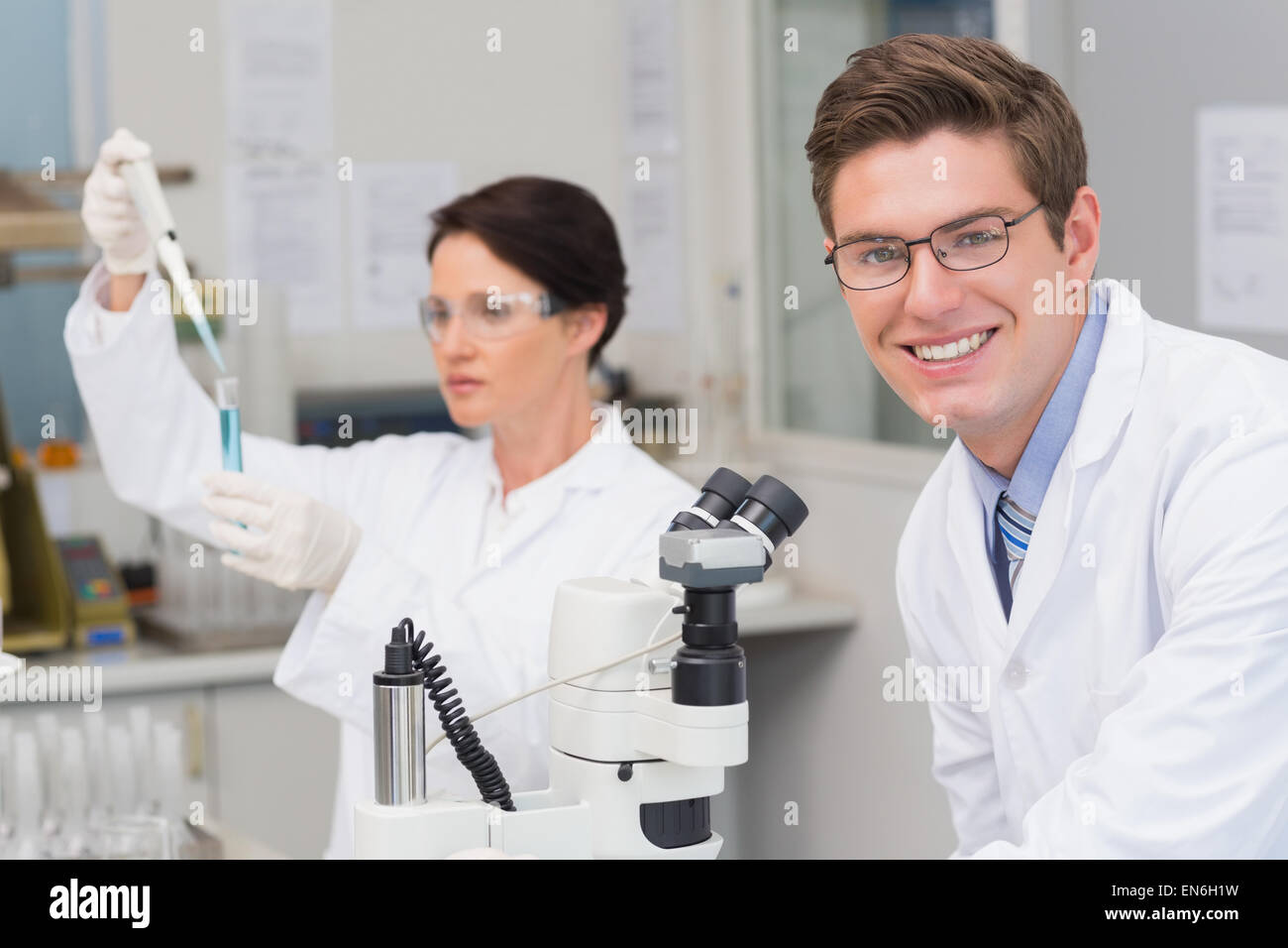 Scientists working with microscope and test tube Stock Photo - Alamy