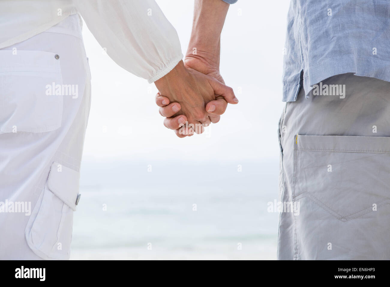 Happy couple holding hands and looking at the sea Stock Photo - Alamy