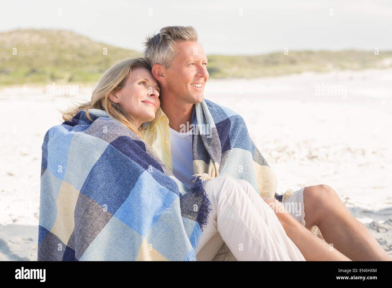 Happy couple wrapped up in blanket Stock Photo - Alamy