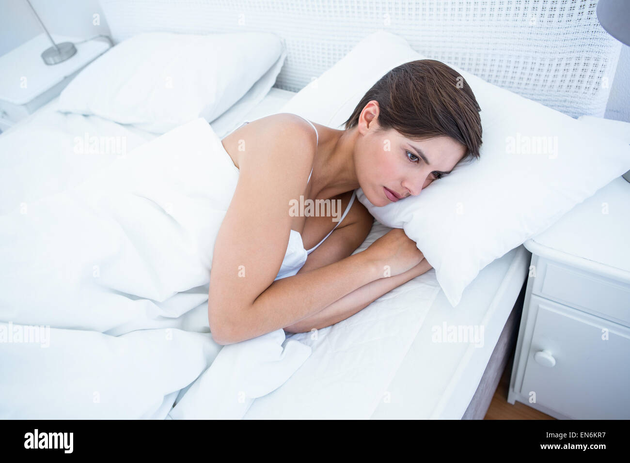 Sad woman lying in her bed Stock Photo - Alamy