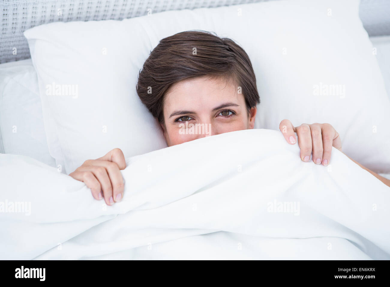 Beautiful woman smiling under the duvet Stock Photo