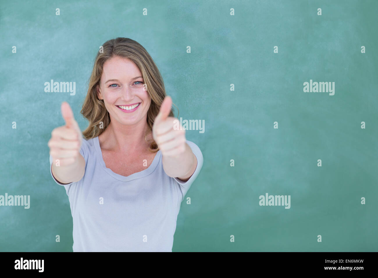 Smiling teacher standing thumbs up in front of blackboard Stock Photo ...