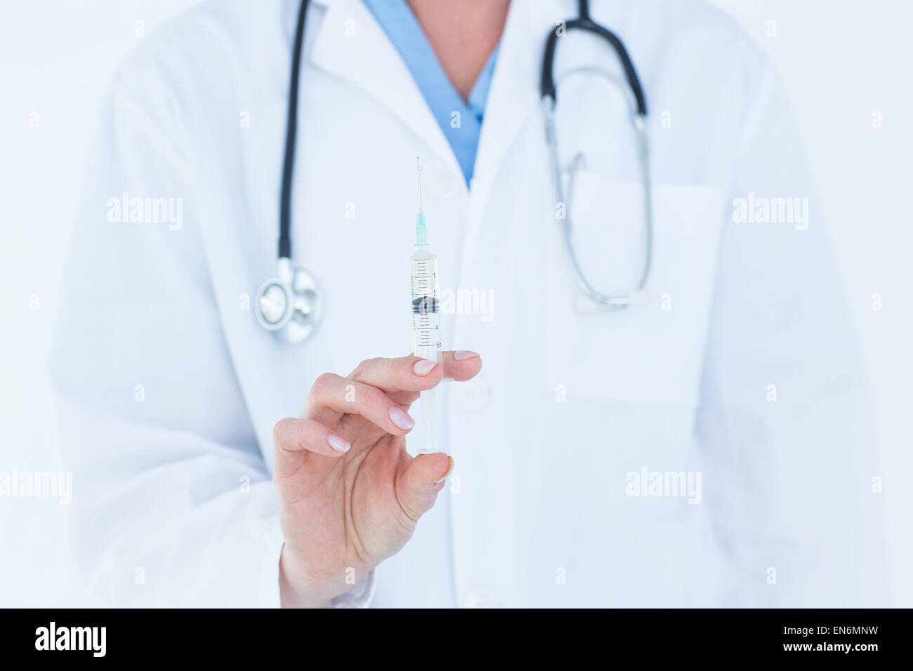 Doctor showing syringe to camera Stock Photo