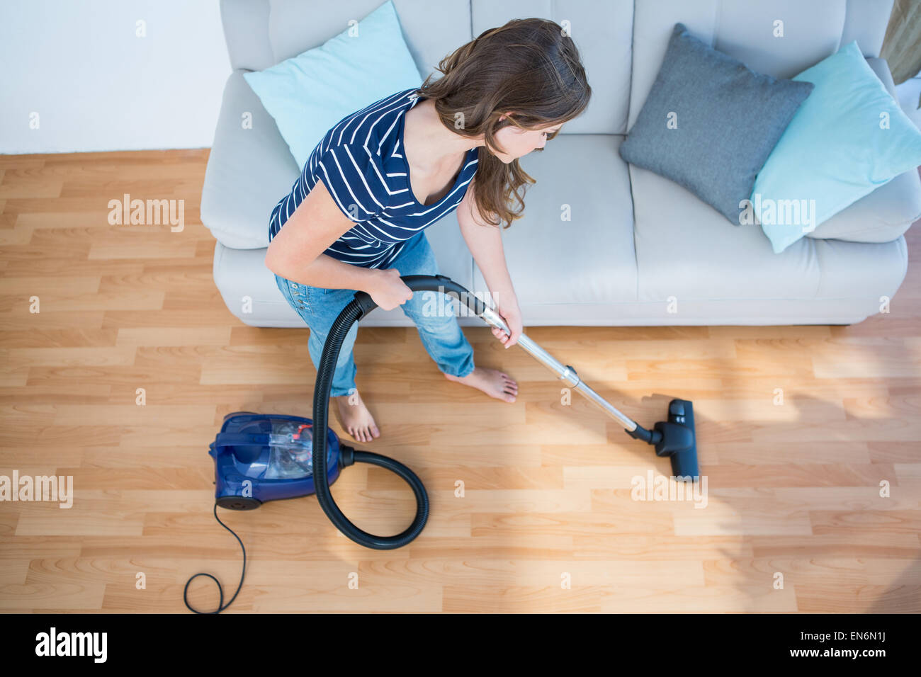 Woman using vacuum cleaner on wooden floor Stock Photo