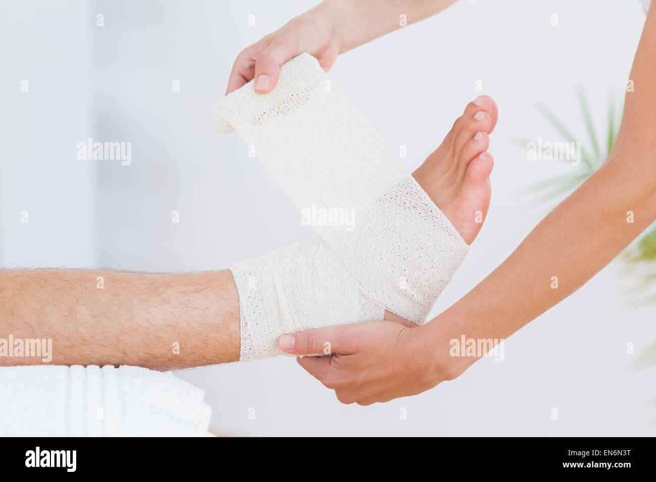 Doctor bandaging her patient ankle Stock Photo