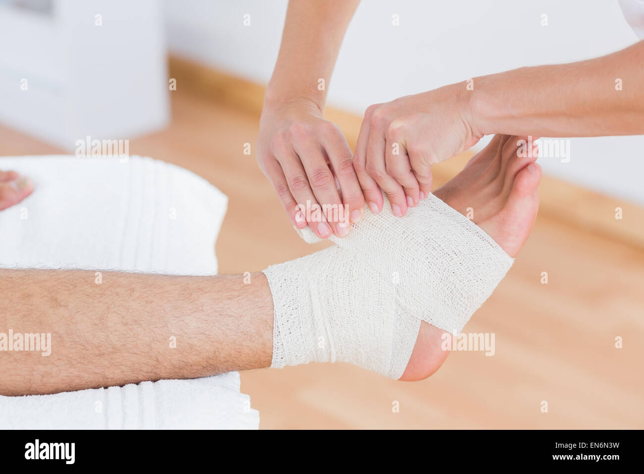 Doctor bandaging her patient ankle Stock Photo